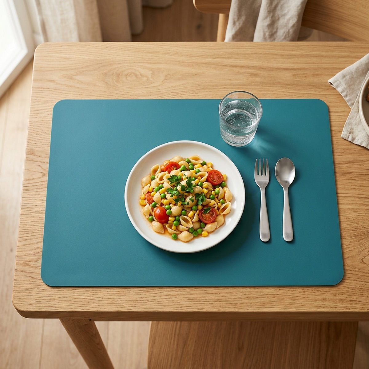 Set de table enfant en silicone vert sur une table en bois avec assiette de pâtes